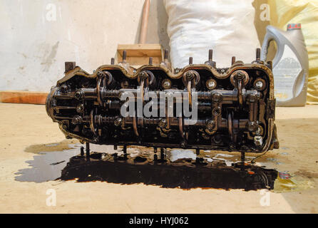 The head of the block of cylinders. The head of the block of cylinders removed from the engine for repair. Parts in engine oil. Car engine repair in t Stock Photo