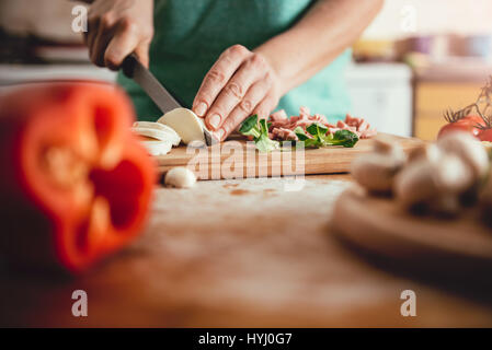 Woman slicing mozzarella cheese on cutting board at the kitchen Stock Photo