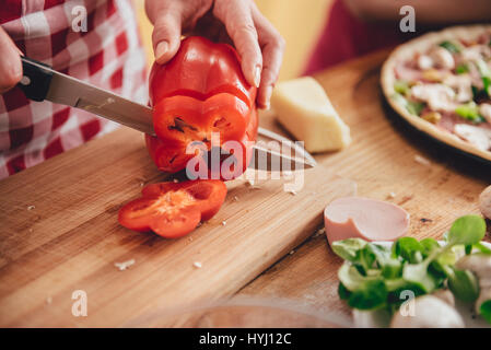 Woman slicing paprika on cutting board at the kitchen Stock Photo