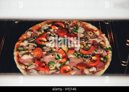 Fresh pizza on a metal baking tray in hot oven Stock Photo