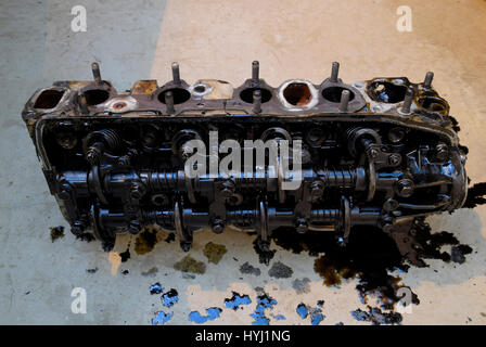 The head of the block of cylinders. The head of the block of cylinders removed from the engine for repair. Parts in engine oil. Car engine repair in t Stock Photo