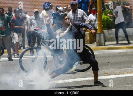 Caracas, Venezuela. 4th Apr, 2017. A demonstrator throws back a tear gas canister during clashes with members of the Bolivarian National Police in Caracas, capital of Venezuela, on April 4, 2017. Supporters of Venezuela's government and opposition parties held marches simultaneously on Tuesday in Caracas, after a clash between the prosecutor-general and the Supreme Court (TSJ) concerning the latter's decision to take over the National Assembly's powers before rescinding it. Credit: Boris Vergara/Xinhua/Alamy Live News Stock Photo