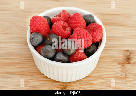 Berry mix of raspberry and blueberry in a white cup. Stock Photo