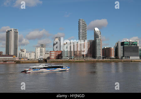A Thames Clipper on the River Thames passes New Providence Wharf on the north bank of the River Thames in London Docklands, UK.