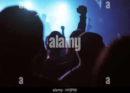 Blur defocused concert crowd as abstract background, people at popular rock music live performance, hands in the air Stock Photo