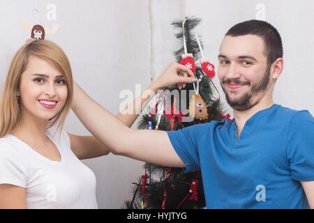 Loving couple hanging decorations on Christmas tree Stock Photo