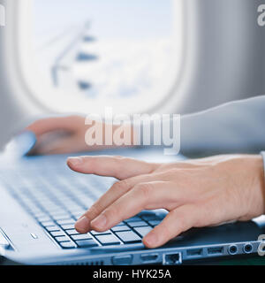 Passenger using laptop in airplane Stock Photo