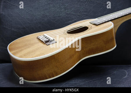 brown wood ukulele on black sofa Stock Photo