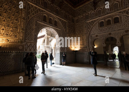 Visitors admiring the Moorish architecture inside the Salon de Embajadores (Hall of Ambassadors) at Real Alcazar ( Royal Palace) originally built by M Stock Photo