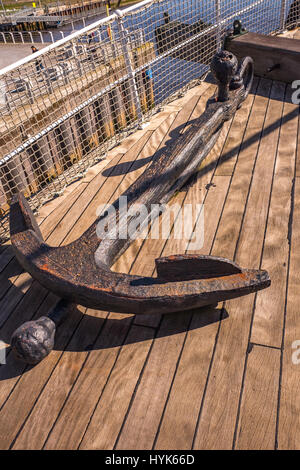 Old rusted anchor on the wooden deck of a tall ship Stock Photo
