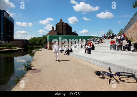 Students from Central St. Martins art school, UAL, enjoying the sun in Granary Square by Regent’s Canal, King’s Cross, London Stock Photo