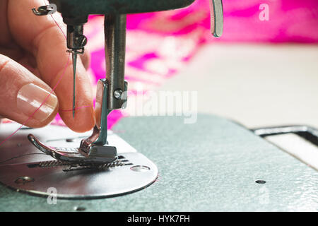 Hands of seamstress threading the needle of a sewing machine. Macro Stock Photo