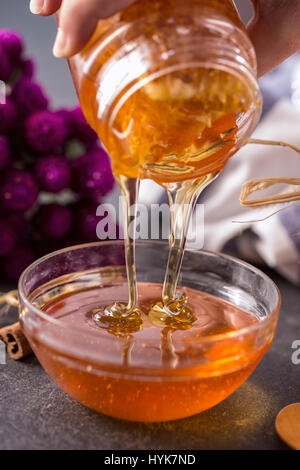 Fresh sweet honey dripping in bowl Stock Photo