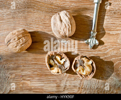 Whole walnuts on light oak table with decorative knife and one opened walnut Stock Photo