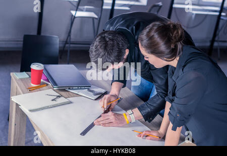 Team of architects people drawing new construction project on desk. business workflow. office concept. Working environment with laptop, coffee, notepa Stock Photo