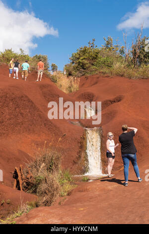 Tourists at a roadside waterfall in red rocks, Koke'e State Park, Waimea Canyon, Kauai, Hawaii, USA Stock Photo