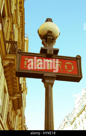 Iconic Paris Metro sign with buildings and blue sky in background Stock Photo