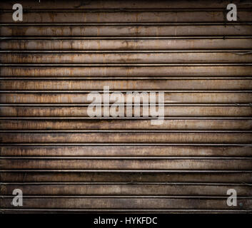 Grungy weathered metallic roll up door. Rusty iron gate. Stock Photo