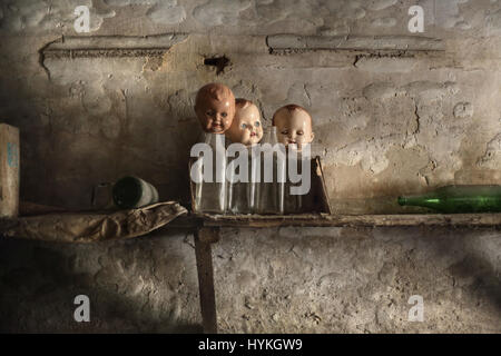 SPOOKY pictures of what could be some of the scariest abandoned places on the planet have been captured. The haunting photos include three ghoulish doll heads propped up onto dusty glass bottles and eerie manikins which look like they are crying black tears. Another ghostly shot shows how funeral caskets have been left to rot. In one image, a forgotten doll sits mysteriously in an old-fashioned pushchair whilst a decaying dentist treatment room stands ominously still. Another picture shows a room of unmade beds which have gone a long time since someone has slept in them. The collection of imag Stock Photo