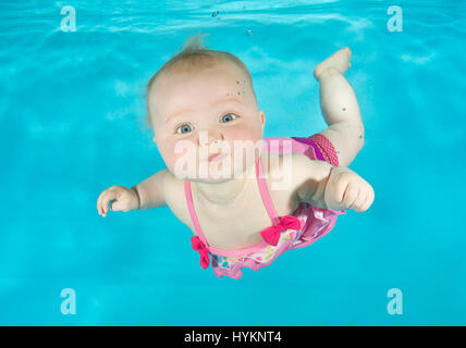 A picture of Lilly-May 8 months old, at an underwater photo shoot with Aquatots Swim School in Gloucestershire. SWIMMING before they can walk these little bathing beauties have been photographed underwater by a British photographer. Utilising their natural amphibious reflex, these babies, aged from just three months old, held their breath as they were released underwater by professional baby swim instructors.  Photographs show the hilarious expressions on the faces of the little nippers. London based underwater photographer Lucy Ray (35) from Starfish Underwater Photography took these pictures Stock Photo