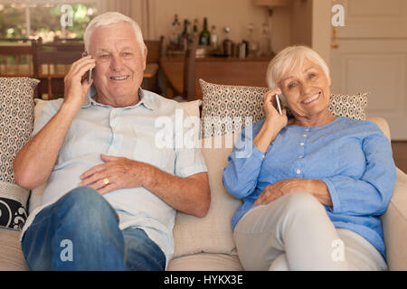 Content senior couple sitting and talking on cellphones at home Stock Photo