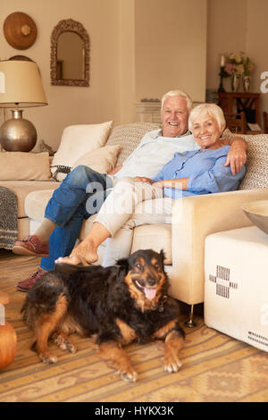 Happy senior couple relaxing with their dog at home Stock Photo