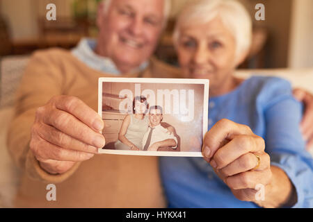 Hands of senior couple holding their youthful photo at home Stock Photo