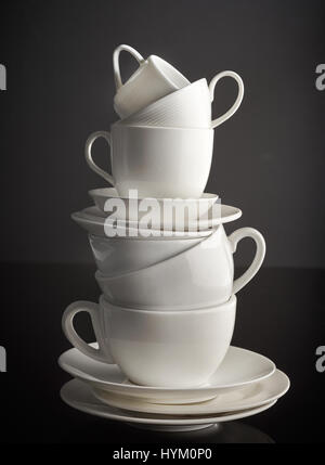 stack of white coffee cups and plates on black background Stock Photo