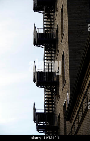 Dean Clough Mills, Halifax, West Yorkshire, Wrought iron fire escape staircase silhouetted against sky Stock Photo