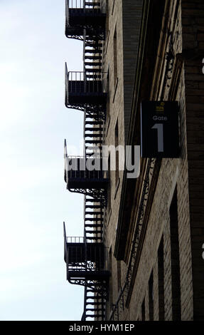 Dean Clough Mills, Halifax, West Yorkshire, Wrought iron fire escape staircase silhouetted against sky Stock Photo