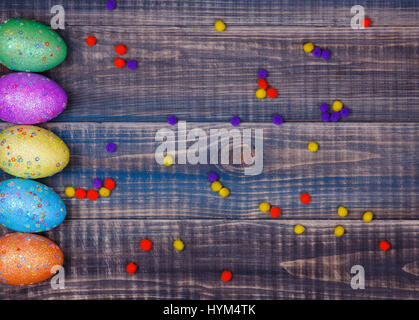 Colored Easter eggs lie in a row on a wooden table. Copy space on the right side. Stock Photo