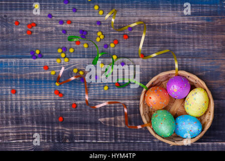 Top view of the Easter eggs lying in the basket. Basket with eggs is on a wooden table. Stock Photo