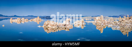 Panoramic view of fascinating tufa rock formations mirrored on calm water surface of famous Mono Lake on a beautiful sunny day with blue sky in summer Stock Photo