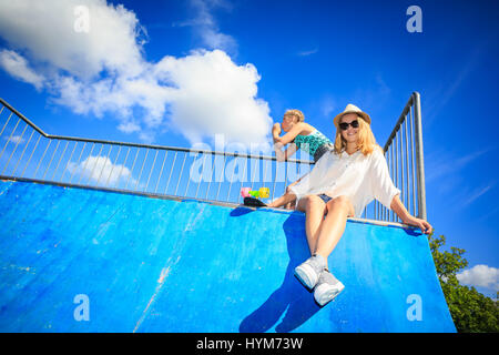 two teenage girls with a skateboard on halfpipe in the park Stock Photo
