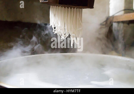 Traditional noodles making procedure on a vintage machine Stock Photo