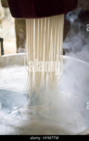 Traditional noodles making procedure on a vintage machine Stock Photo