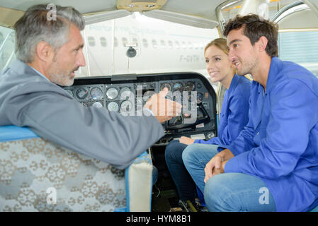 Teacher talking to students in aircraft cockpit Stock Photo