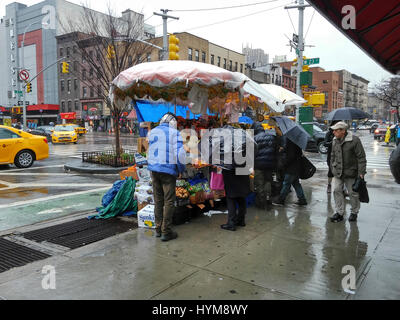 New Yorkers brave the rain to buy their fruits and vegetables from a produce vendor in the Chelsea neighborhood of New York on Friday, March 31, 2017. New York was hit with drenching rain and cold weather all day and the depressing precipitation is expected to continue into Saturday.  (© Richard B. Levine) Stock Photo