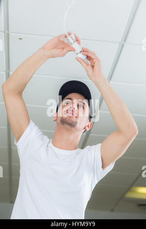 handsome young builder installing light bulb indoors Stock Photo