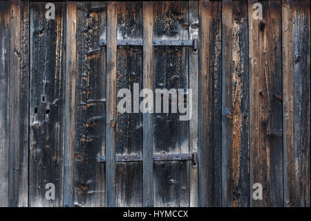 Closed weather worn dilapidated wooden doors entrance in wood paneled building Stock Photo