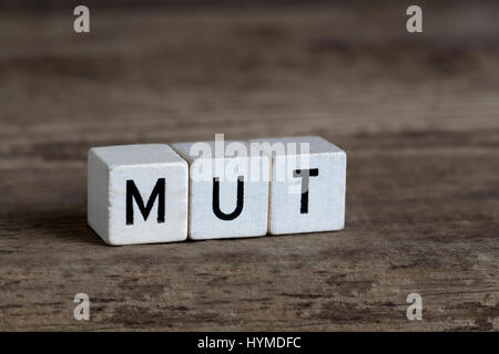 German word courage, written in cubes on a wooden background Stock Photo