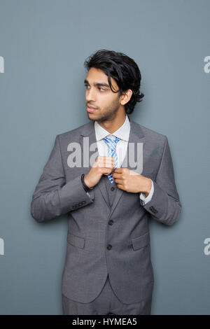 Portrait of a handsome young businessman standing against gray background Stock Photo