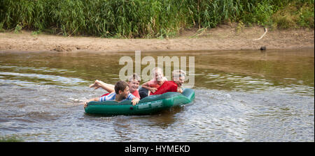 Four kids floating down the Pilica River on an inflatable raft. Polish girl age 8, boys ages 10, 11, 12. Rzeczyca Central Poland Europe Stock Photo