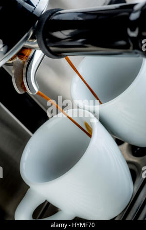 Traditional pump espresso coffee machine pouring shot into two white cups Stock Photo
