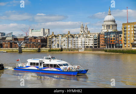 Blue and white Catamaran Thames Clipper boat, part of the river bus service, Bankside Pier, St Paul's Cathedral in the background, on a fine sunny day Stock Photo
