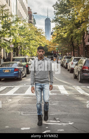 A portrait of a young, black man walking infront of New York City's World Trade Center. Shot during the Autumn  of 2016. Stock Photo