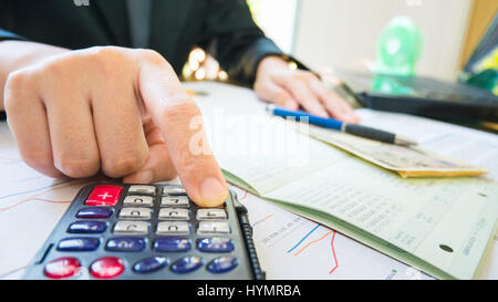 Business woman hand hold pen and use calculator on Statement or financial report in business concept. Stock Photo