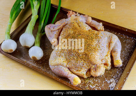 Whole Raw Chicken in iron pan marinated and ready to cook with ingredients for cooking. on stone background. Stock Photo