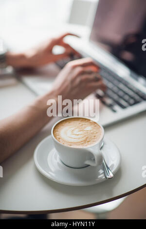 Woman using a laptop during a coffee break, hands close up. Stock Photo