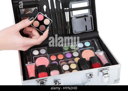 Opened aluminum make up case and female hand holding an eyeshadow palette Stock Photo